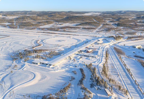 Aerial view of a vast, snow-covered winter landscape with multiple prepared driving and test tracks.